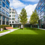 Modern office park with green lawn, trees and bench Colleges & Universities
